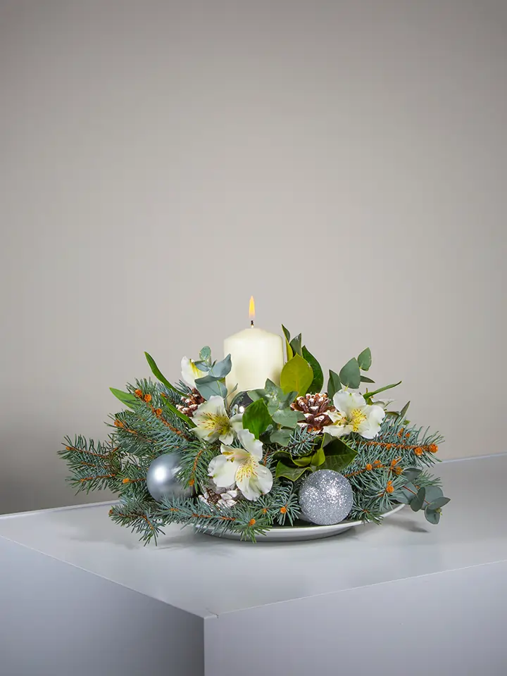 Centrotavola di fiori bianchi elementi natalizi e candela bianca